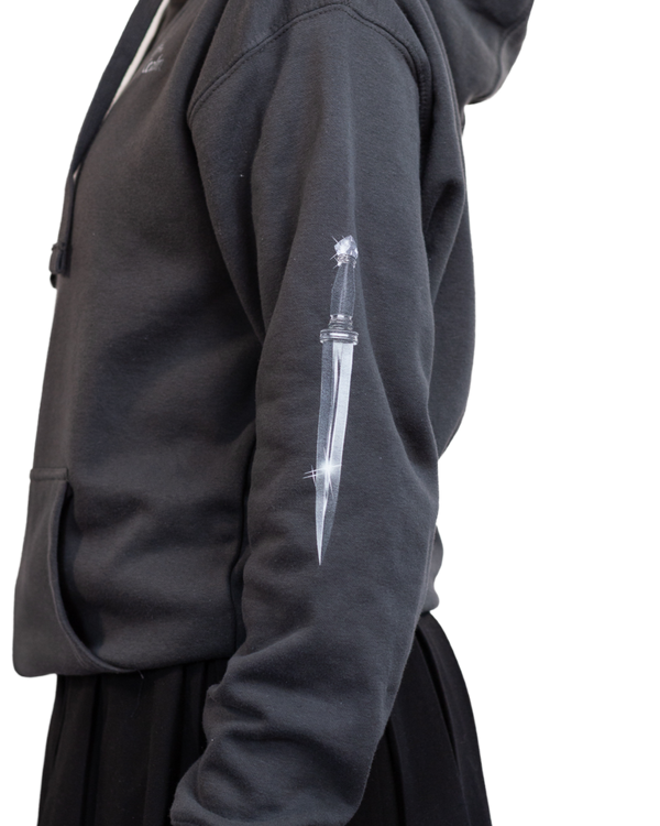 Person wearing a dark gray hoodie with a white dagger design on the sleeve against a white background
